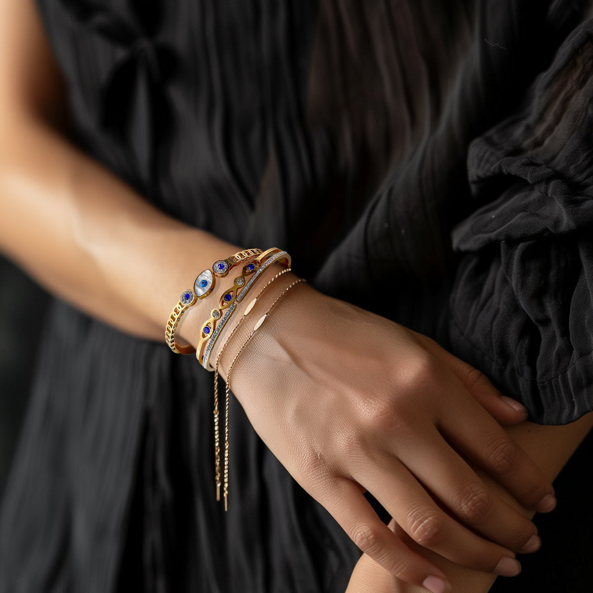 Gold Evil Eye bracelet styled with other layered bracelets on model's wrist