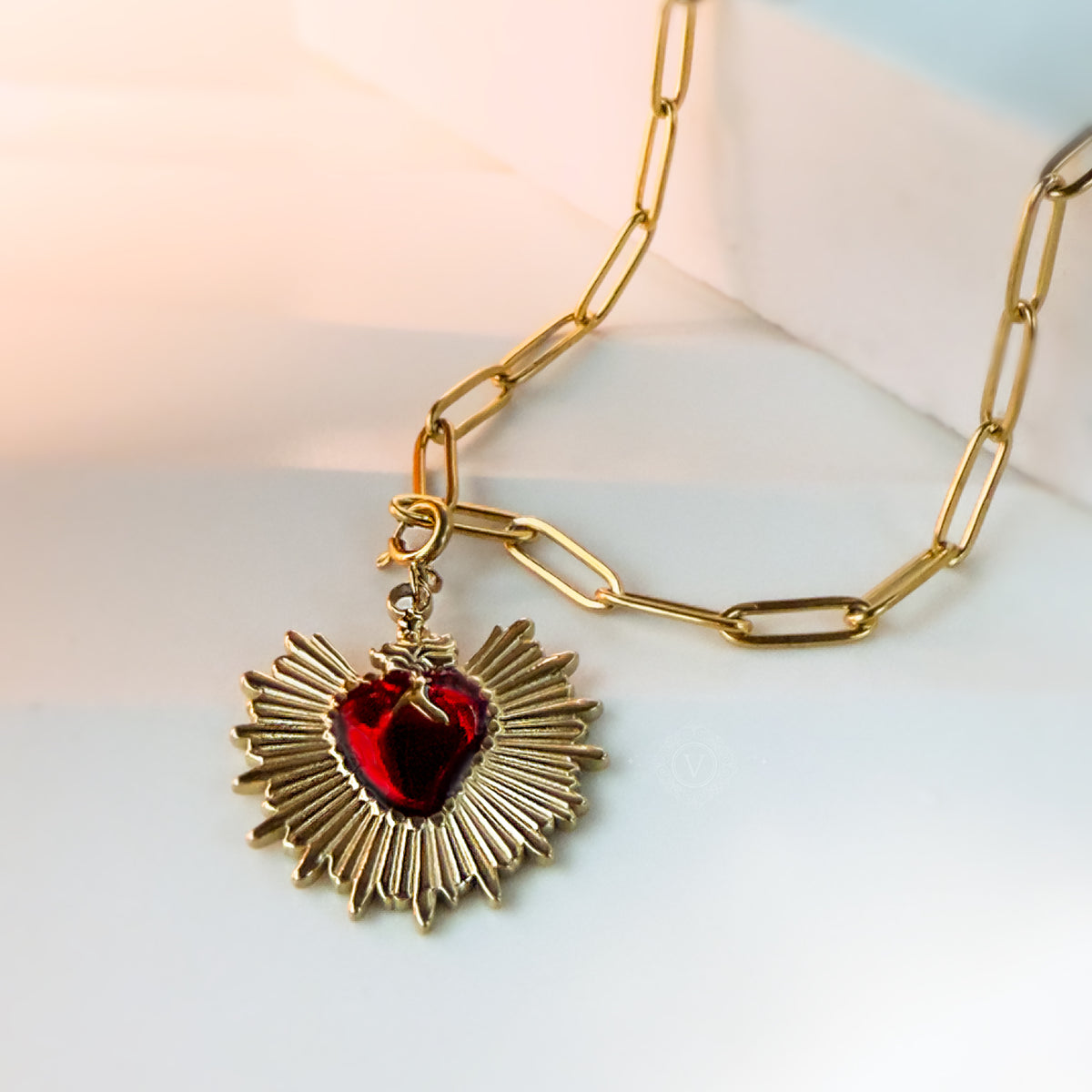 Close-up of the Eloria necklace showing the thick paperclip chain and radiant red enamel Sacred Heart pendant.