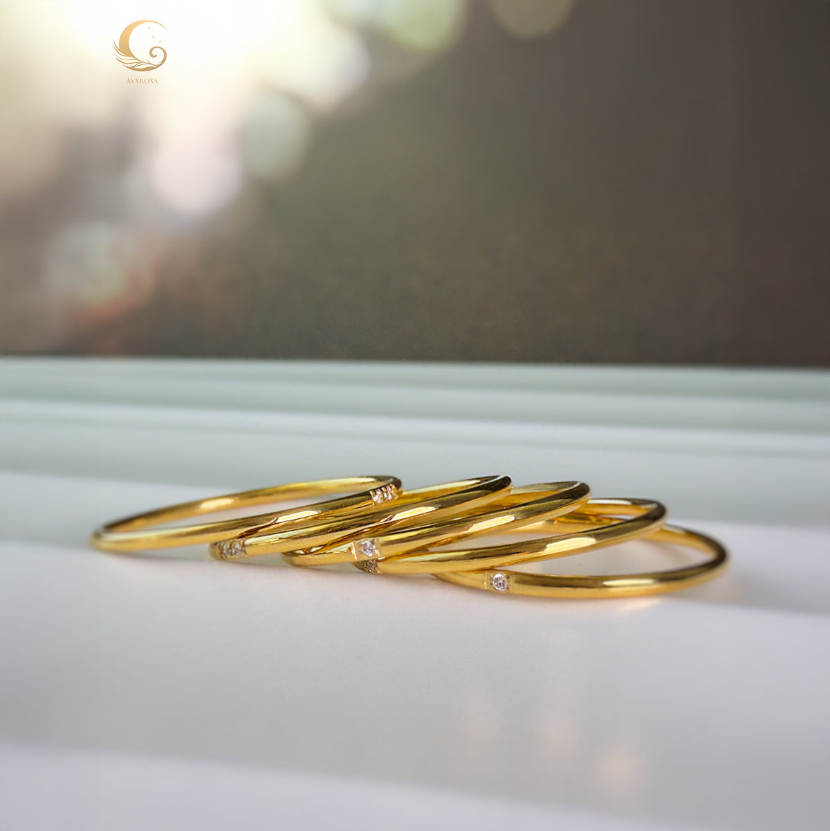 Five minimalist gold zircon rings laid side by side on a white surface