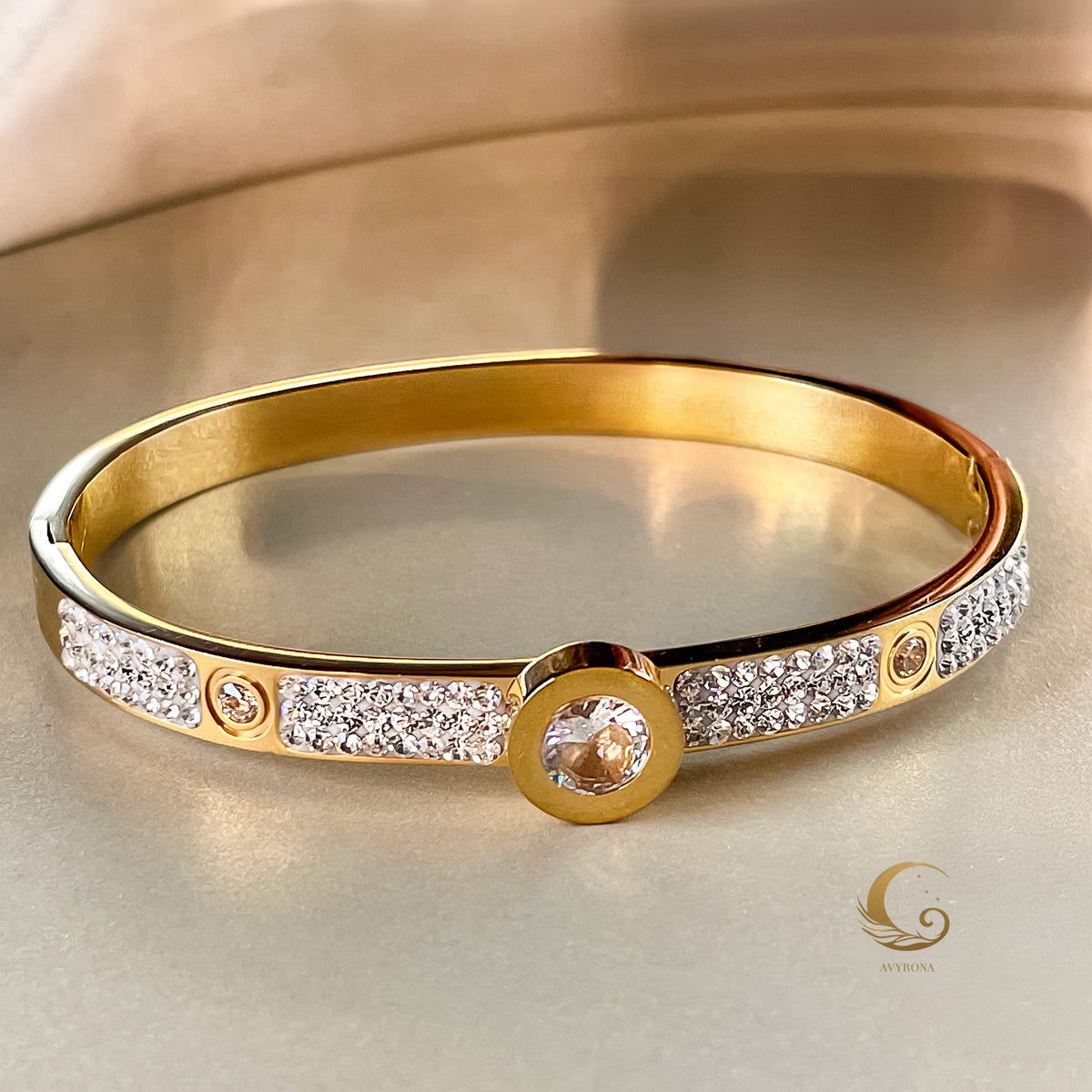 Gold bracelet on a satin background, showcasing sparkle and refined crystal details with central round zirconia centerpiece.