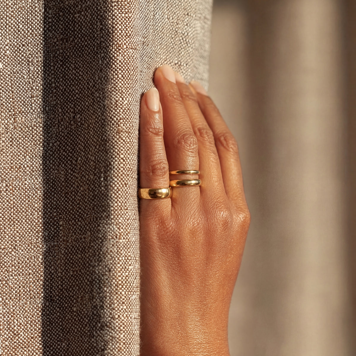 Hand wearing a gold ring on a textured surface