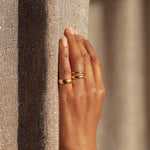 Hand wearing a gold ring on a textured surface