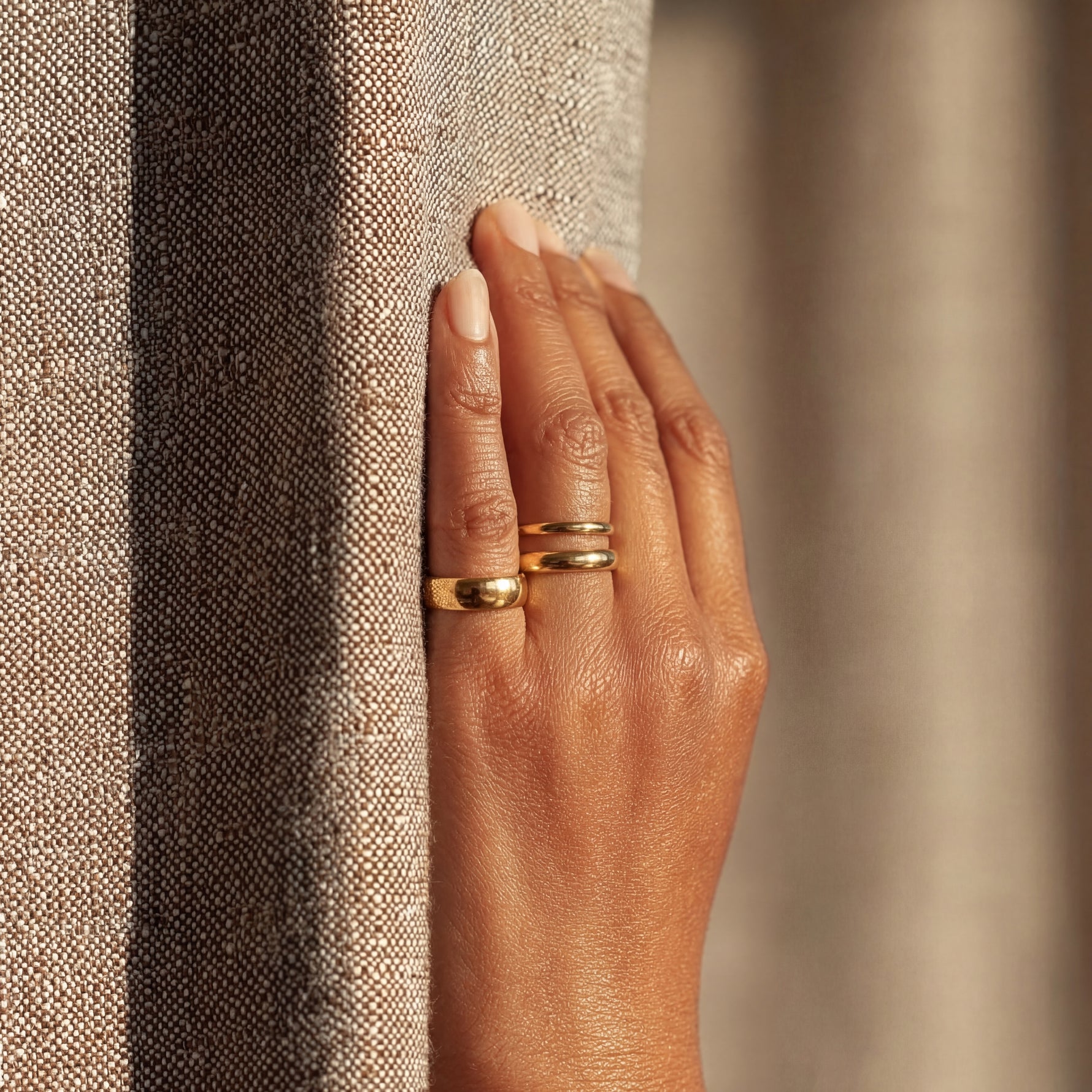 Hand wearing a gold ring on a textured surface