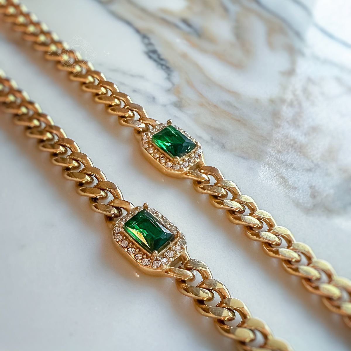 Harper Necklace and Bracelet set with green crystals and cuban chains, laid side by side on white marble background.