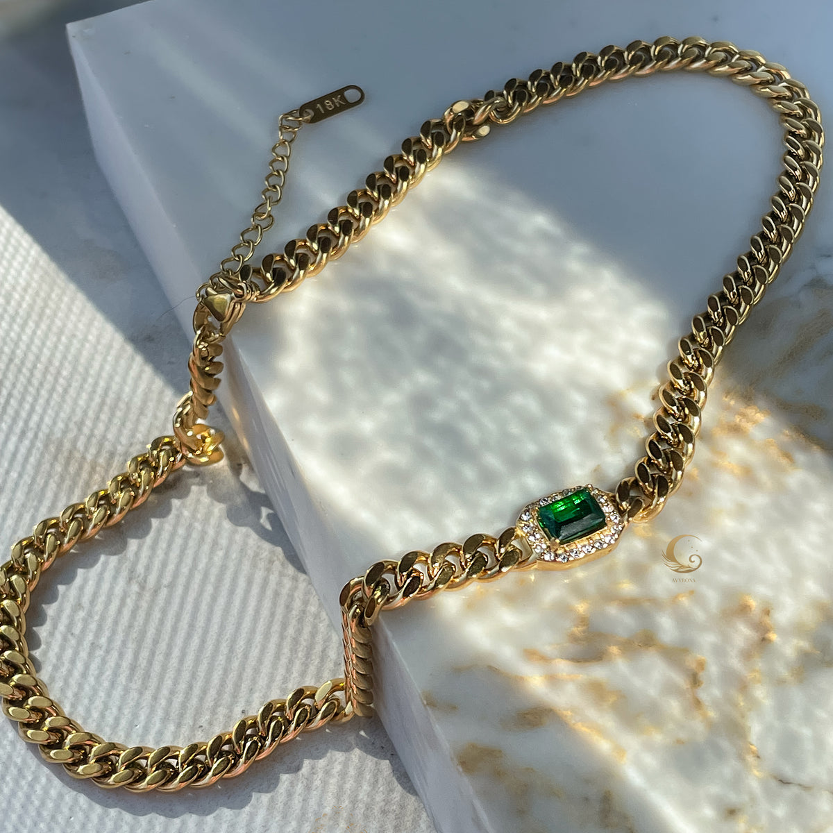 Full view of Harper Necklace with green crystal centerpiece and extension clasp, styled on marble corner.