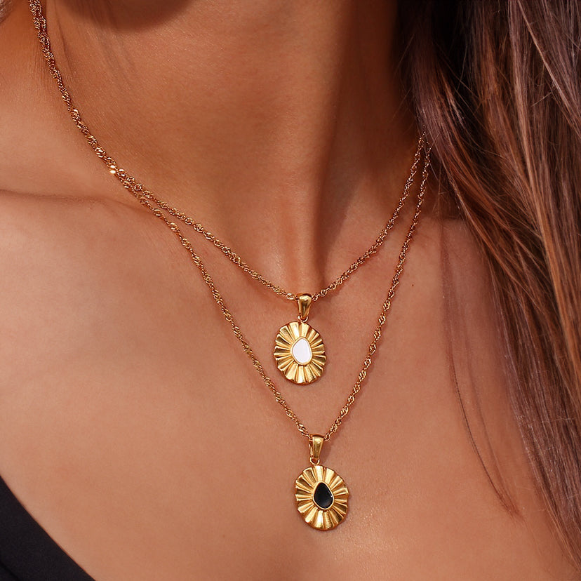Model wearing two layered necklaces – Liore Black Flower Necklace and matching gold floral pendant. The styling highlights the elegant shine and versatile look of both pieces on the neckline.