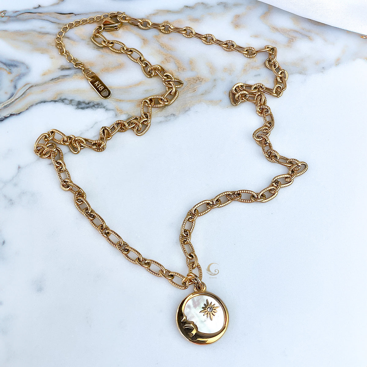  Full Lyra necklace with puffed mariner chain laid out on marble surface.