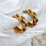 Margaret floral-inspired hoop earrings crafted in rich 18K gold-plated stainless steel, elegantly displayed on soft fabric.