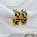 Pair of Margaret gold hoop earrings showcasing bold floral petal design, beautifully styled against luxurious silky background.