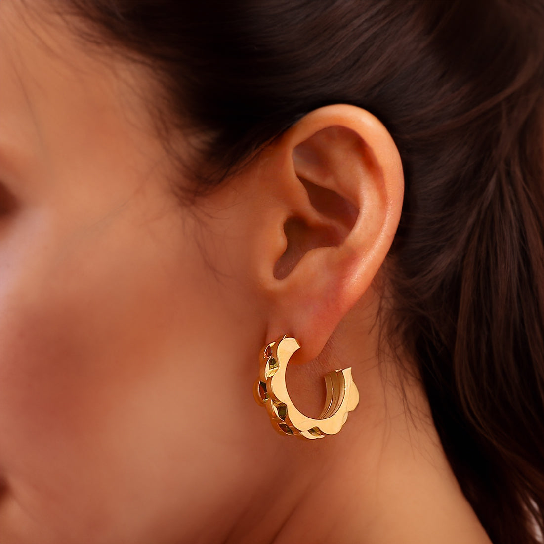 Model wearing Margaret bold floral hoop earrings in 18K gold, demonstrating their size and striking design on ear.