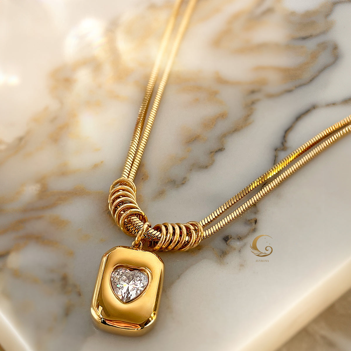Margaret necklace displayed diagonally on marble with soft shadow and full pendant details visible.