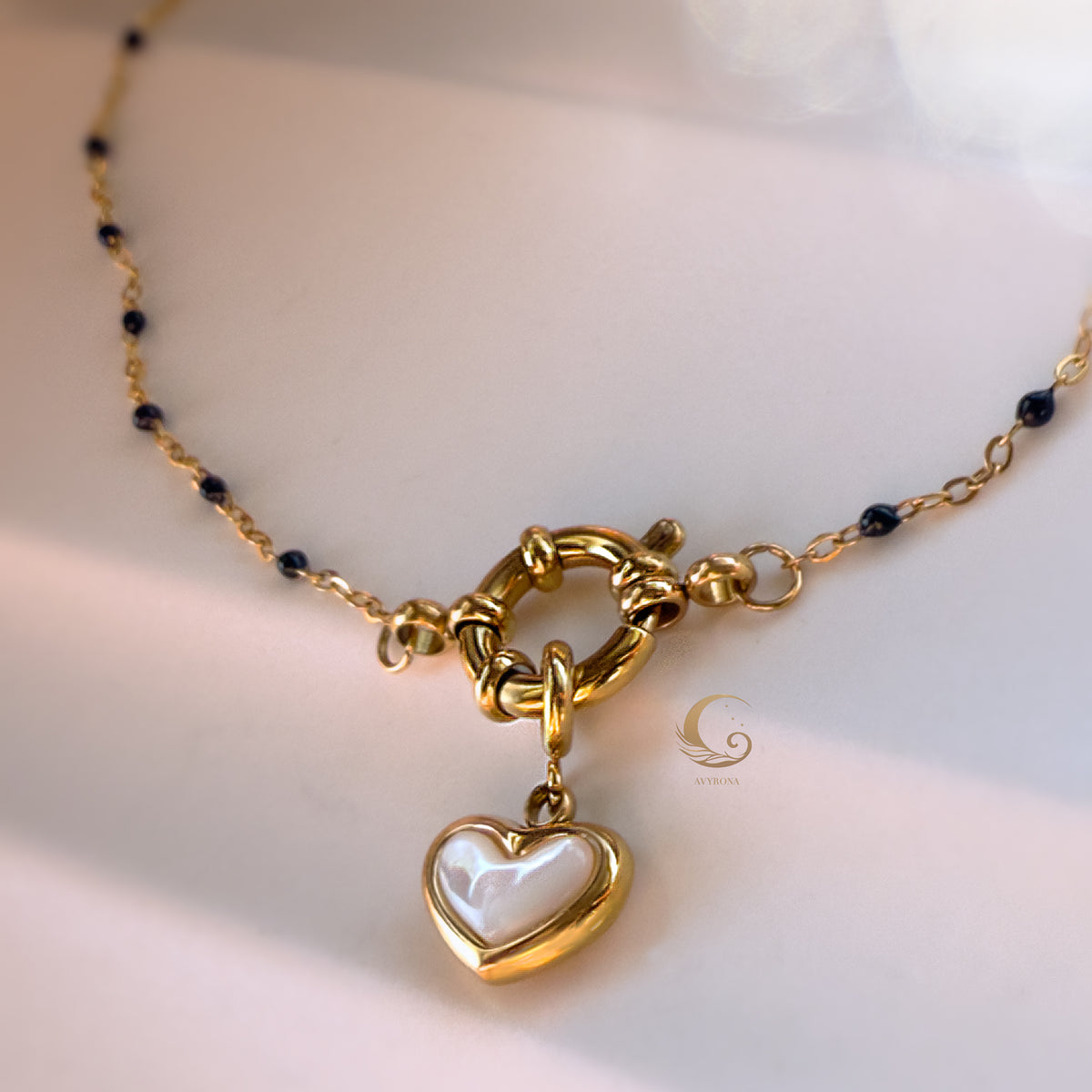  Zoomed-in shot of the necklace clasp and heart charm against skin-toned background, showing fine chain detail.