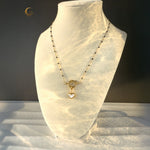 Navy and gold heart necklace shown on white jewelry stand, with wavy light patterns across the display.