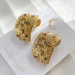 Celestial hoop earrings laid on branded Avyrona card, showing cosmic design with moon, eye, and star symbols in colorful accents.