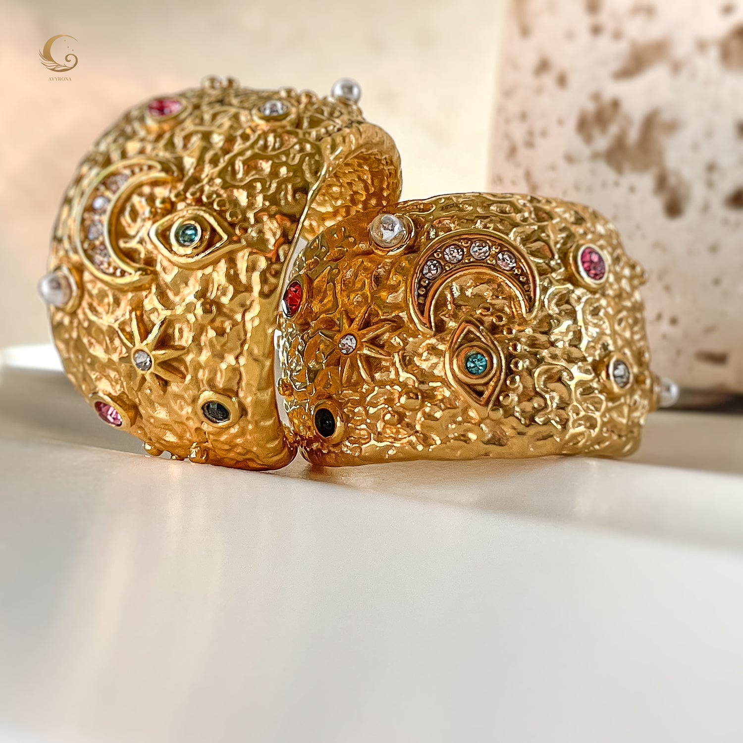 Side view of moon and evil eye earrings with hammered gold finish and multiple colored stones, captured on neutral background.