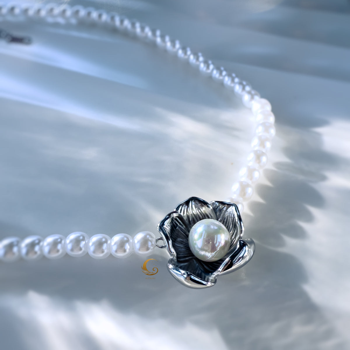 Close-up of silver floral pendant with pearl centerpiece