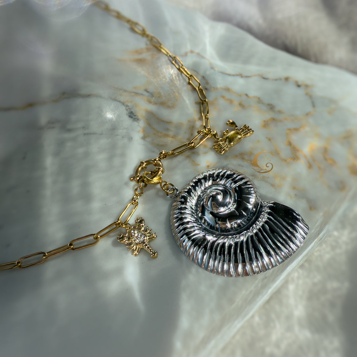 Nerida necklace flat lay with silver shell and gold sea charms in bright natural light