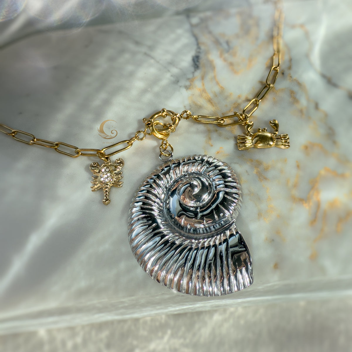 Nerida necklace laid out with toggle clasp, large silver shell and ocean charms