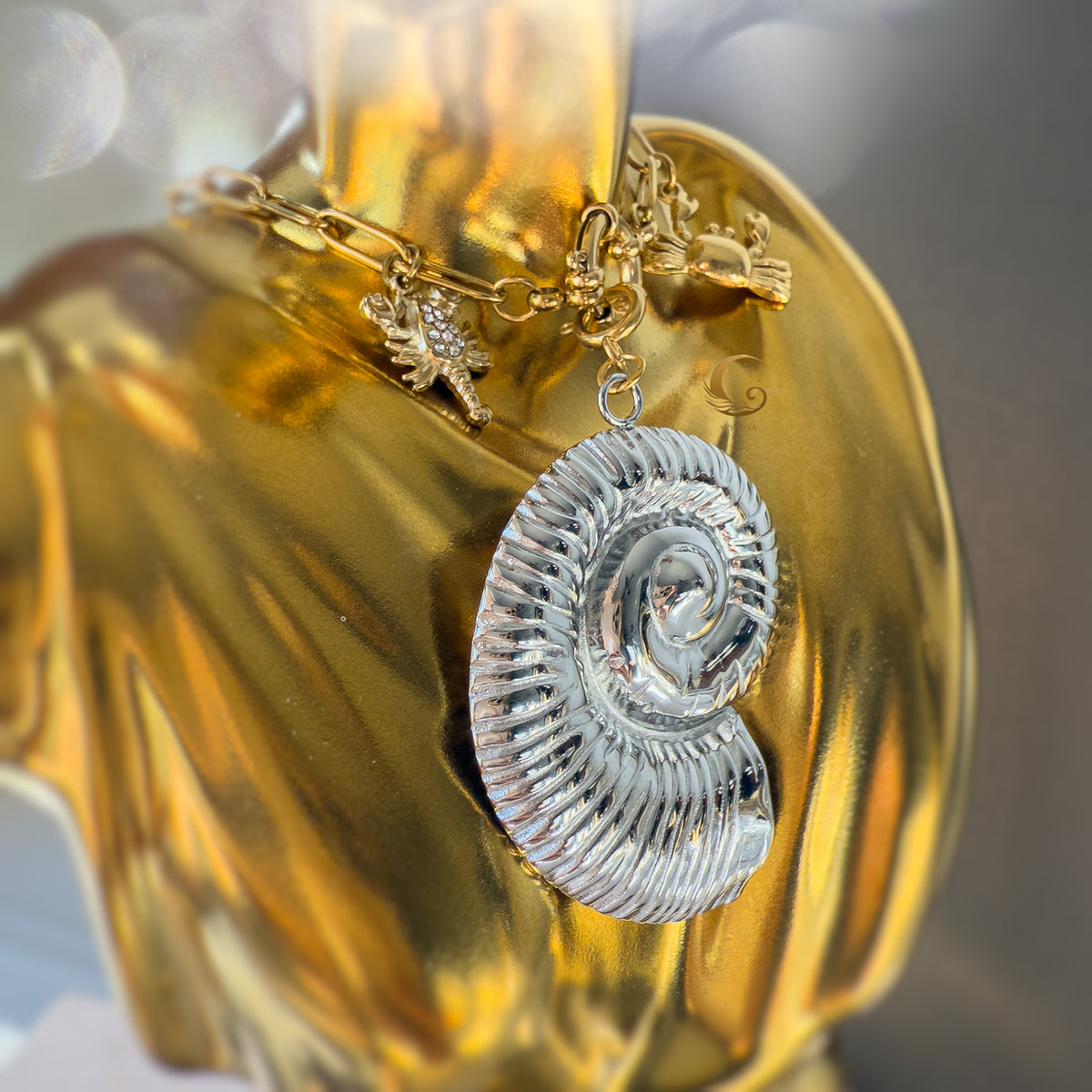 Nerida necklace styled on gold fabric, silver shell pendant and sea creature charms