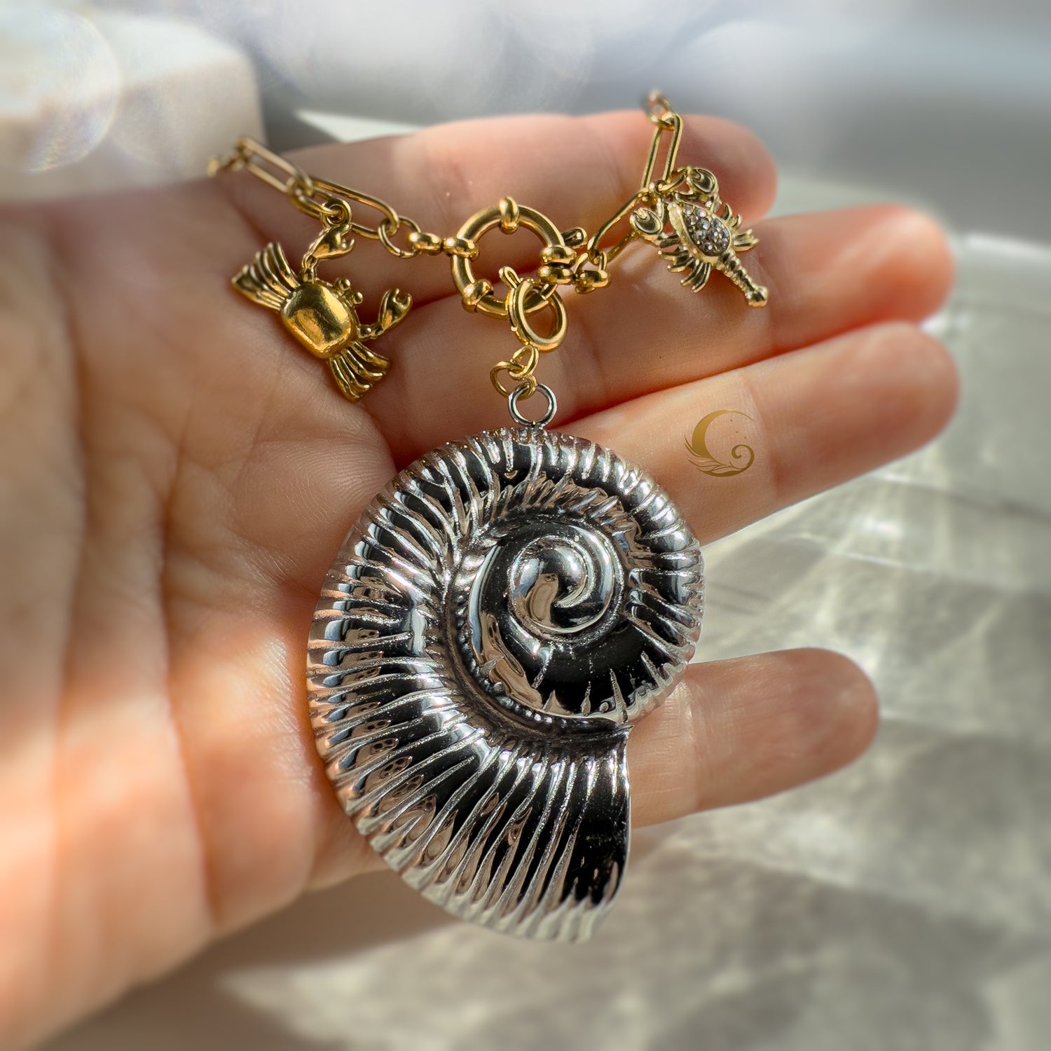 Nerida silver shell necklace held in hand, showcasing texture and golden sea creatures