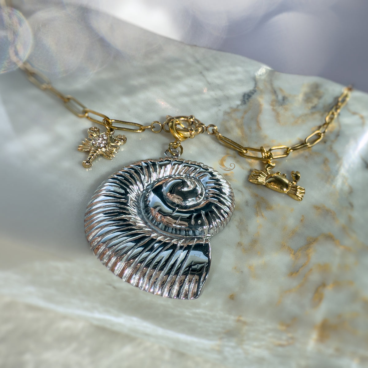 Nerida necklace showing toggle clasp, silver shell, gold crab and lobster on marble