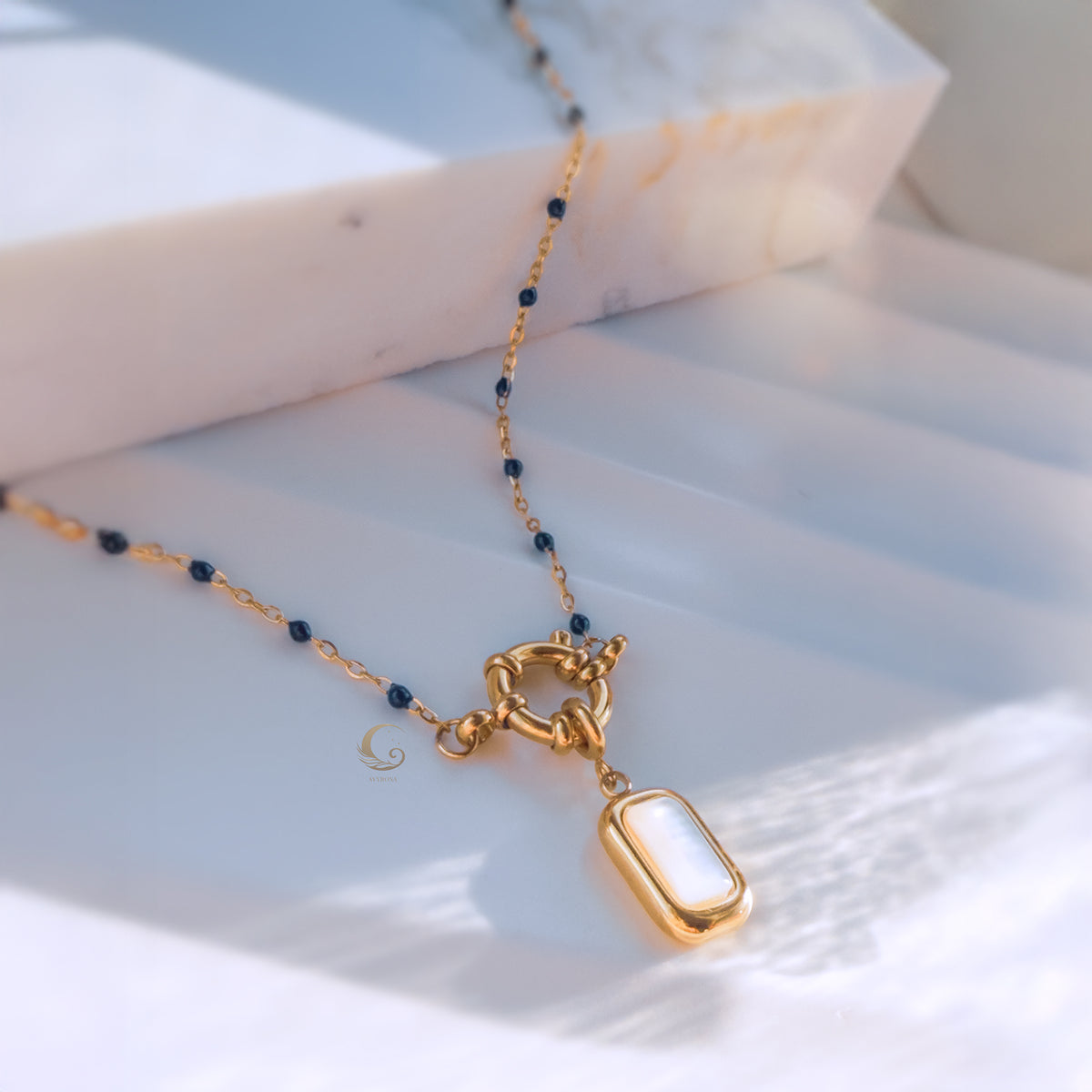 Nerina necklace laid flat on soft white fabric, showcasing the toggle clasp and deep blue beaded chain