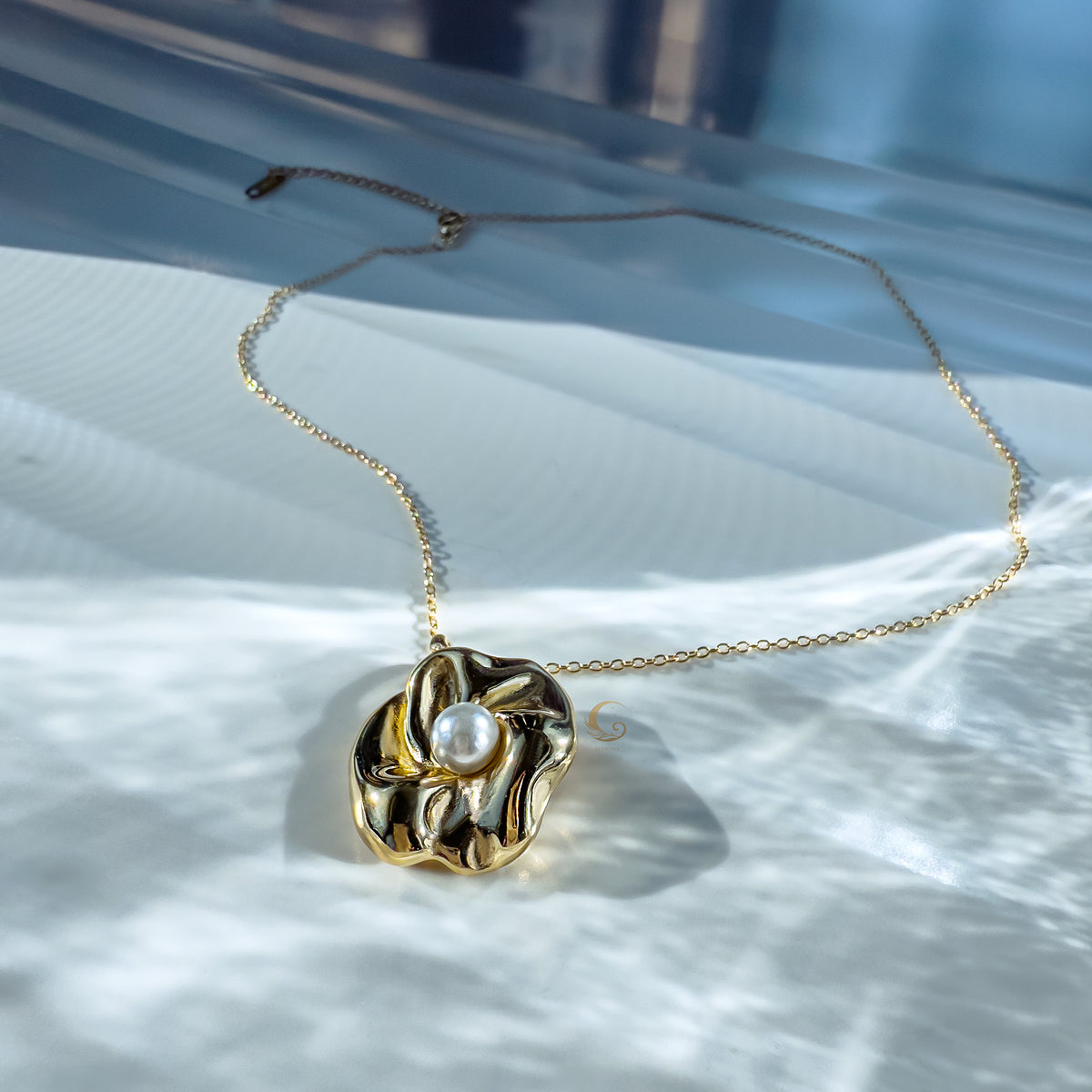 Nymira necklace glowing on a white surface with soft water reflections