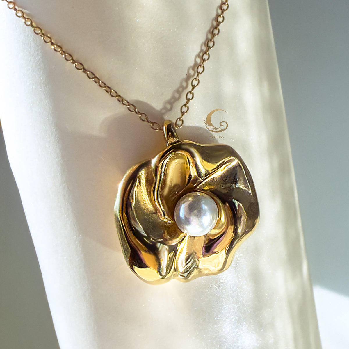 Front view of Nymira necklace pendant, gold flower design with central pearl