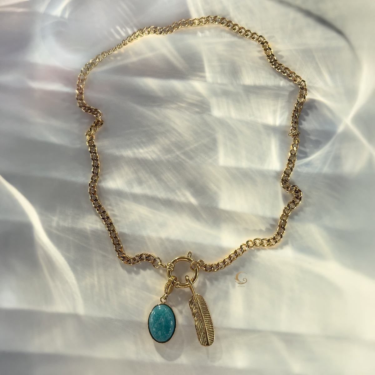 Flat-lay of gold toggle chain necklace with turquoise pendant and feather charm
