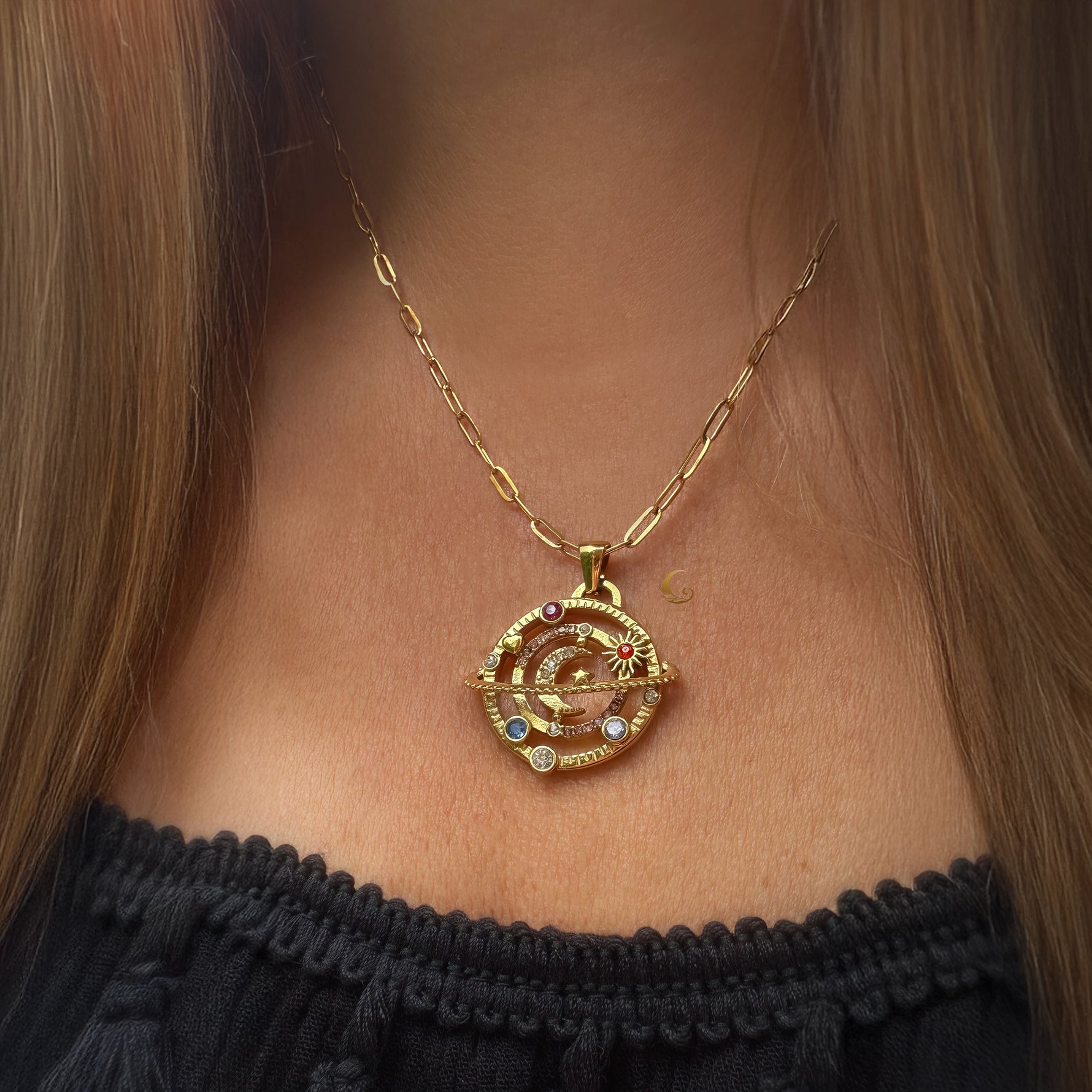 Gold celestial orbit moon necklace on model wearing black top, photographed in natural light.