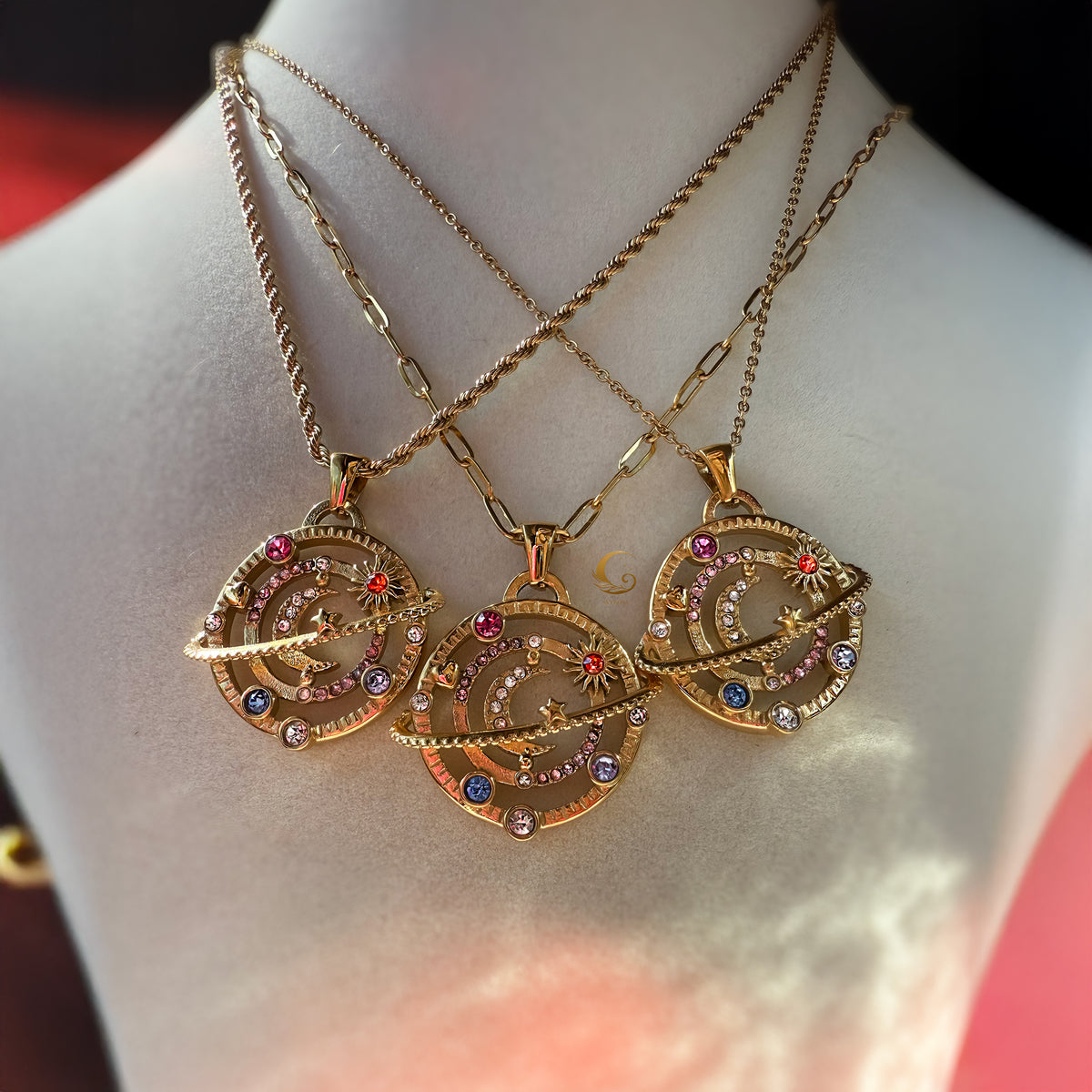 Three gold orbit moon necklaces on display, showing paperclip, rope, and link chains in warm golden tones.