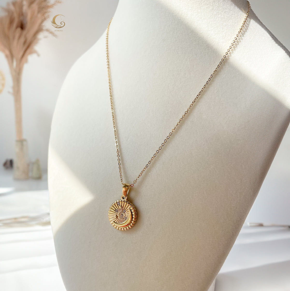 Selene Crescent Moon Necklace displayed on a white jewelry bust, featuring a gold-plated chain and crescent pendant with sparkling zirconia accents.