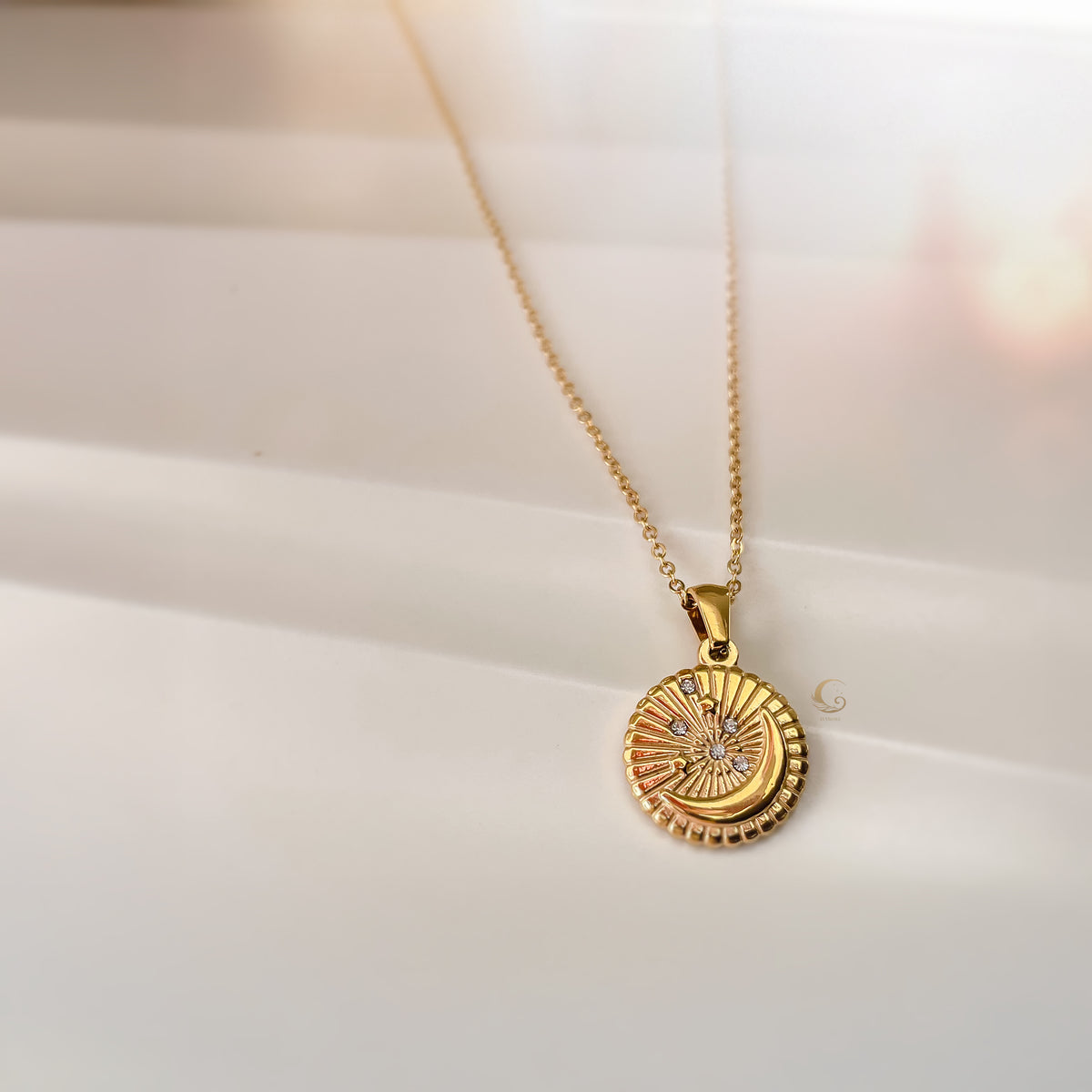 Close-up of Selene Crescent Moon Necklace lying flat on a soft white fabric, showing the detailed gold crescent pendant with sparkling zirconia stars.