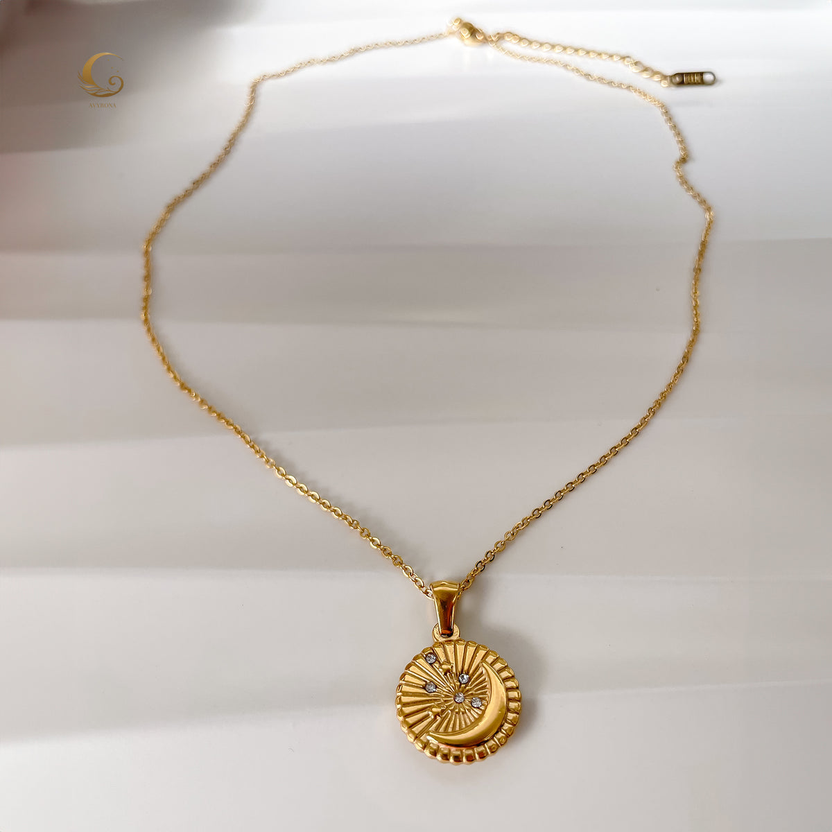 Full view of Selene Crescent Moon Necklace laid flat, showing the complete gold-plated chain, adjustable extension, and detailed pendant with sparkling zirconia stars.