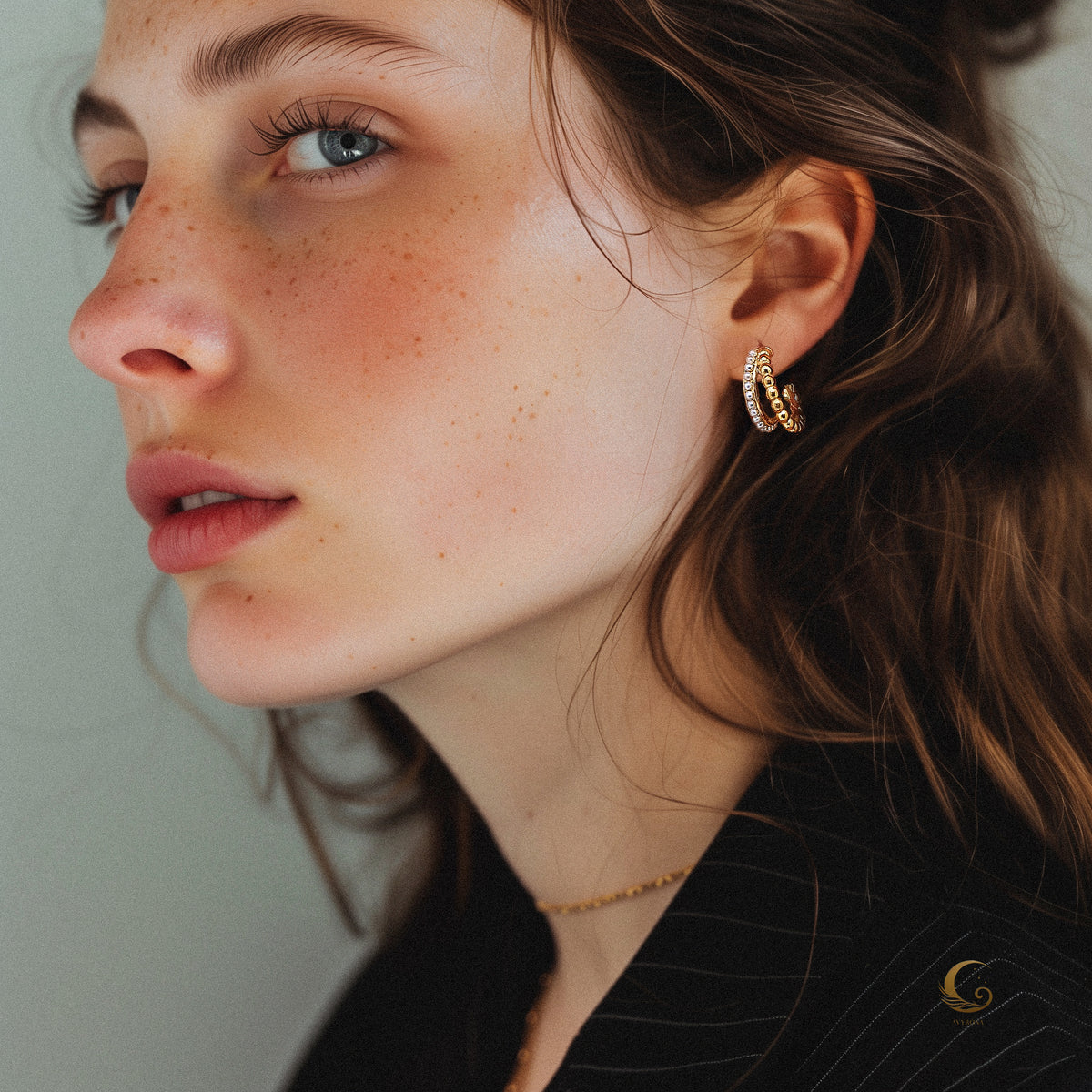 Woman wearing Serina dual pearl hoop earrings in gold, elegant side portrait with natural light