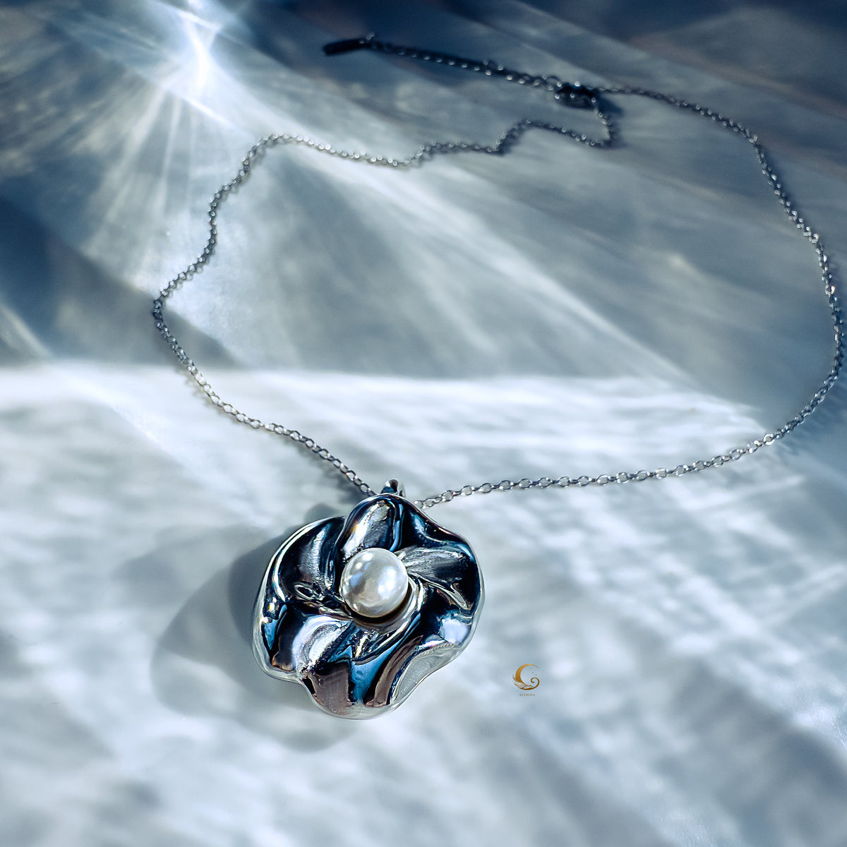 Silver flower necklace with pearl glowing under soft water-reflected light