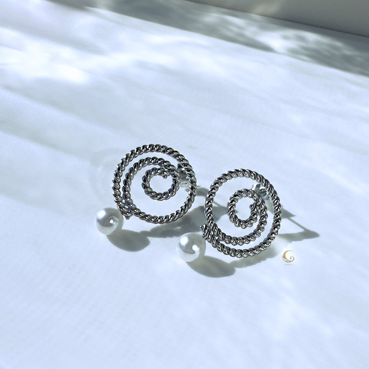 Silver Thaleia earrings resting on bright background with subtle shadows