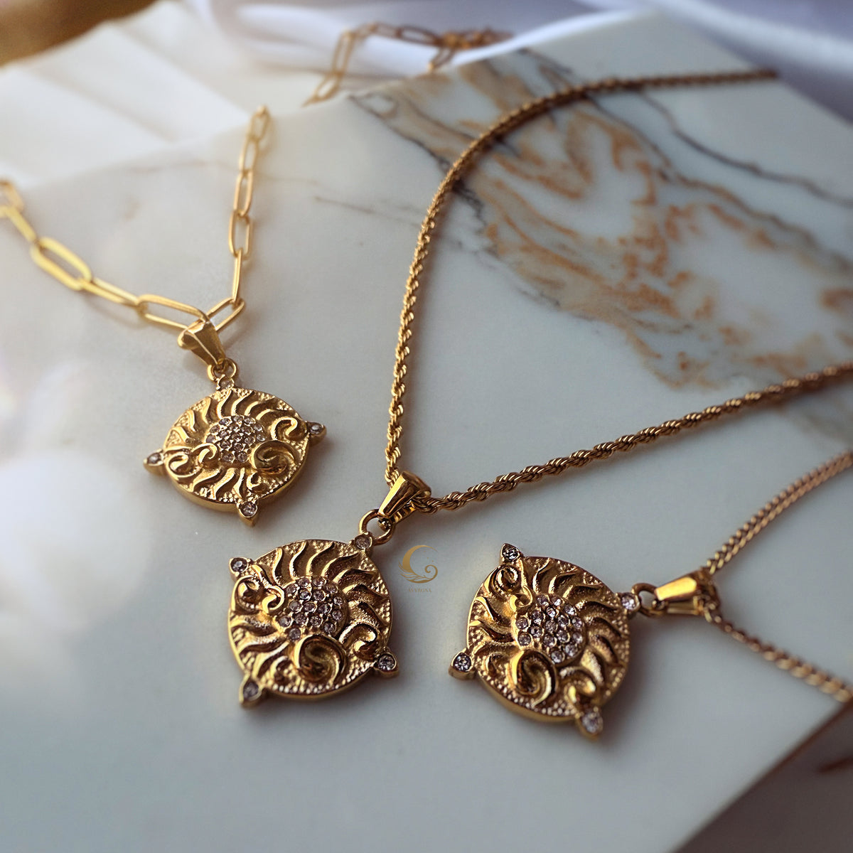 Golden sun medallion necklaces catching the light on marble background — vintage glow meets modern elegance