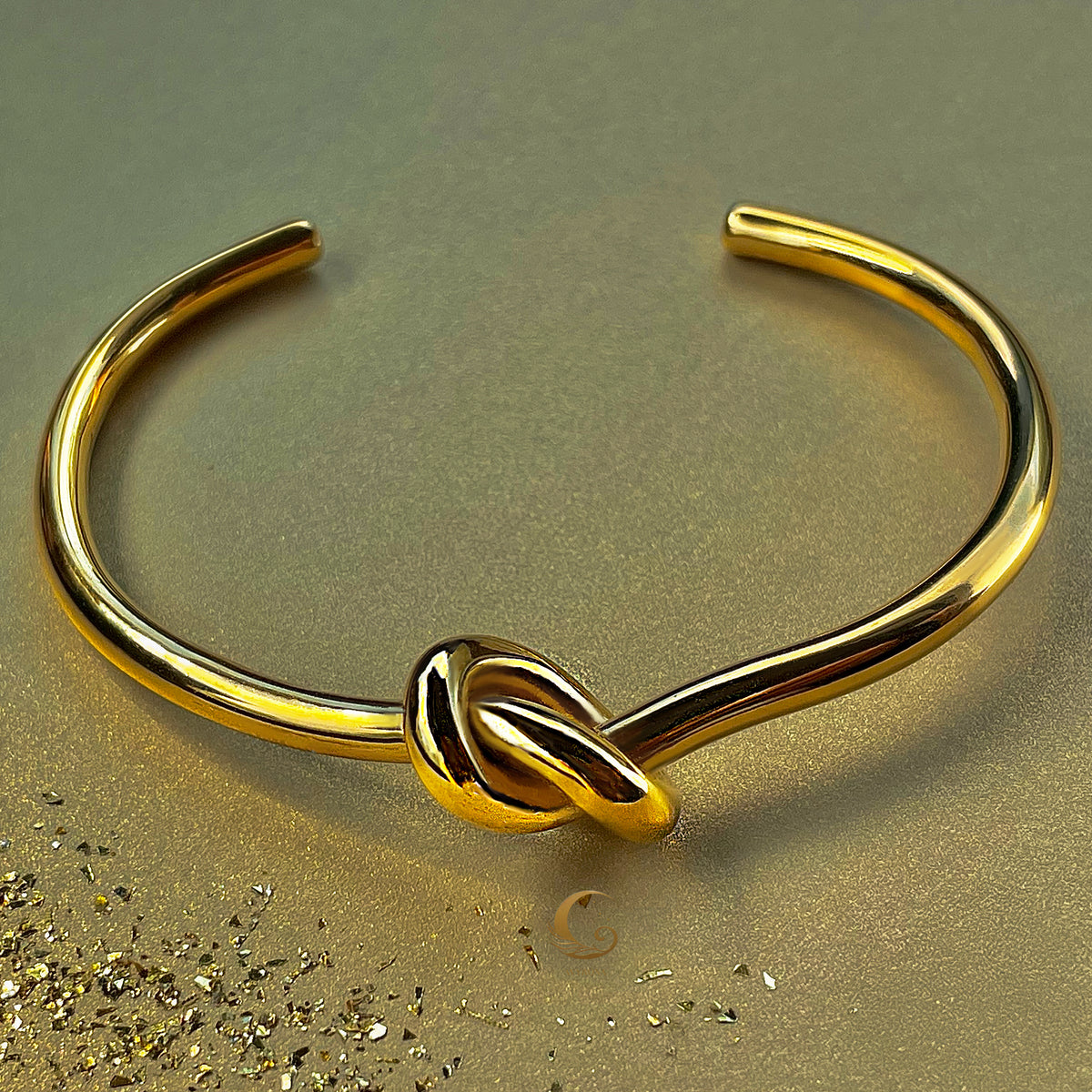 Elegant gold knot bracelet on golden background, open bangle design symbolizing unity – Avyrona