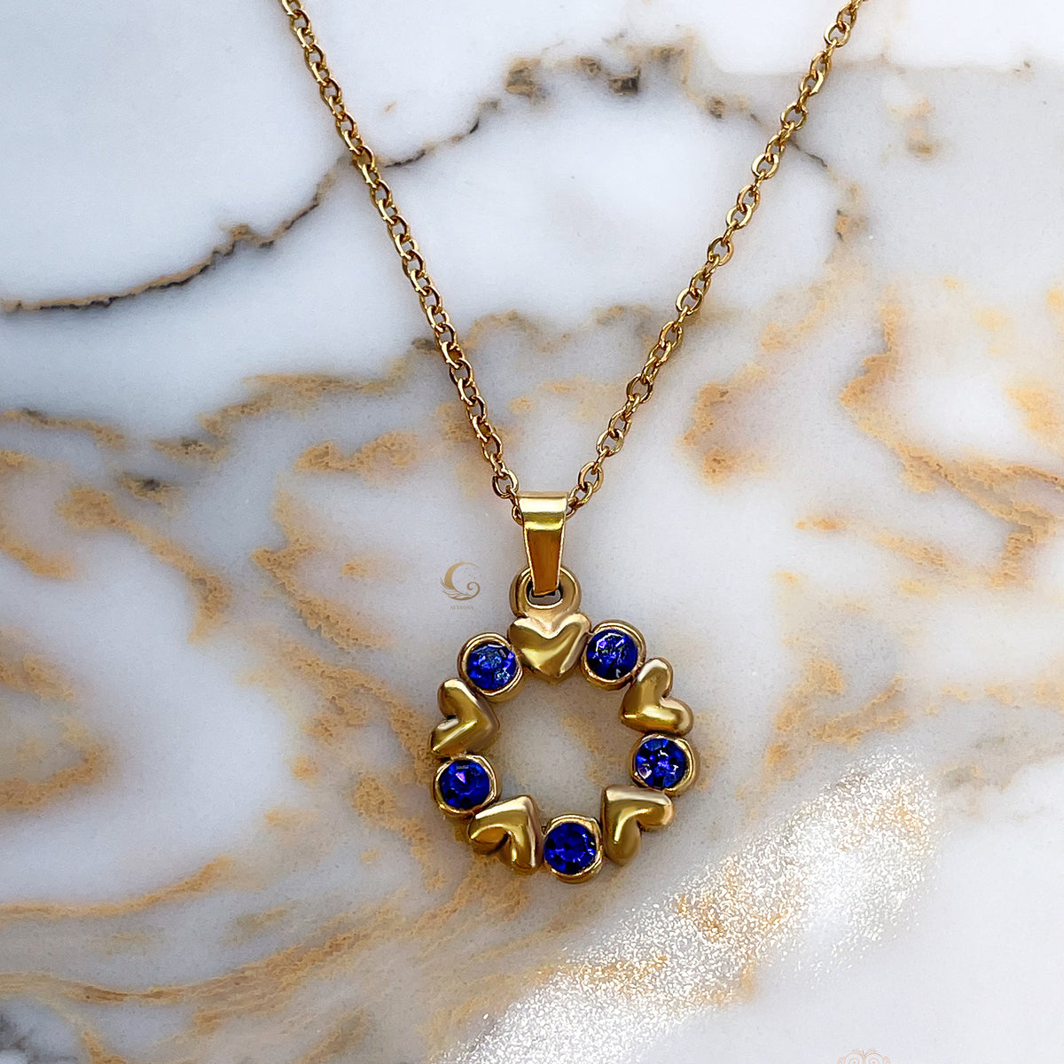 Flat-lay of Vega necklace on white marble, highlighting the delicate link chain and full pendant detail